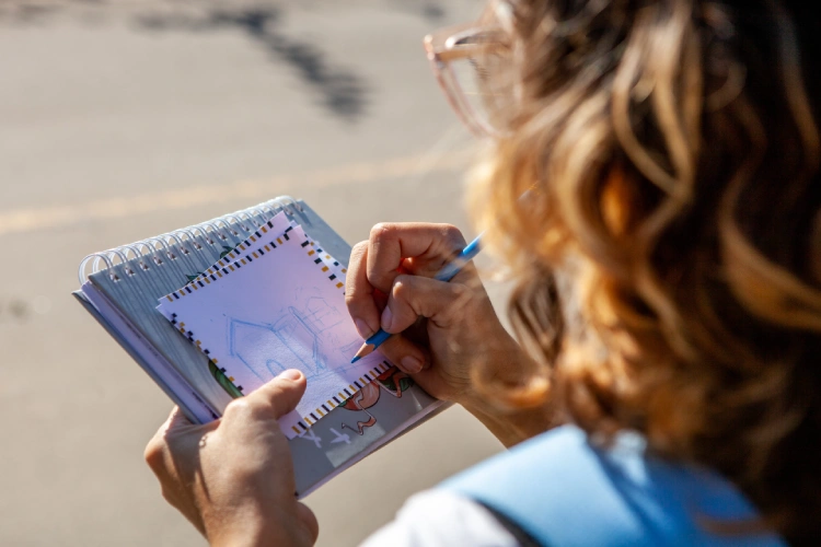 Menina desenhando uma casa em atividade ao ar livre