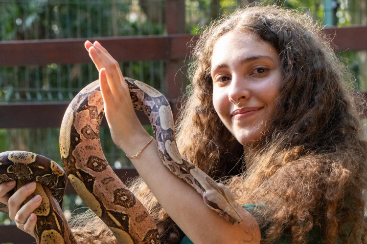 Menina segurando serpente ao ar livre